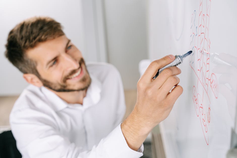 A professional man writing ideas on a whiteboard in a modern office setting.